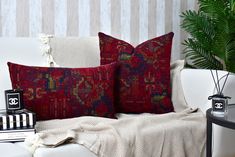 two red pillows sitting on top of a white couch next to a black and white table