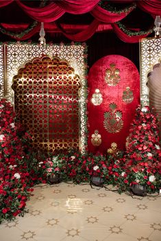 an elaborately decorated stage with red and white flowers on the floor, surrounded by greenery