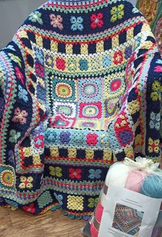 a crocheted chair sitting on top of a wooden floor next to a pile of yarn