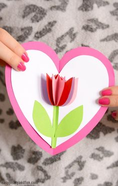 a woman holding up a paper heart with a flower on it