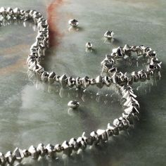 a silver necklace and earring laying on top of a table next to each other