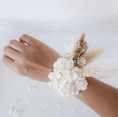 a woman's hand with a flower and feather wrist corsage