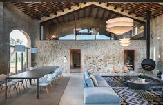 a living room filled with furniture and a large stone wall next to a dining table