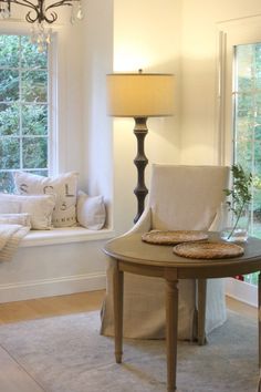 a living room filled with furniture next to a window sill and a lamp on top of a table