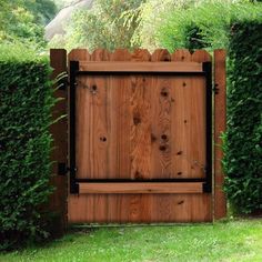 a wooden gate in the middle of some bushes