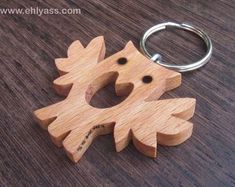 a wooden keychain shaped like a dog on a wood table with a metal ring