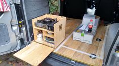 the back end of a van with an open hatchback door and shelves filled with various items