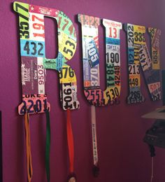 the letters are made out of license plates and lanyards hanging on a purple wall