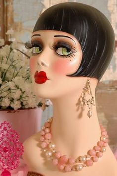 a mannequin head with necklaces and earrings on it's face next to flowers