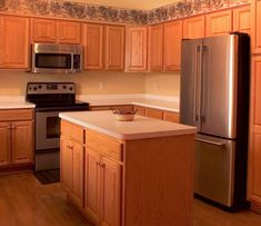 an empty kitchen with stainless steel appliances and wood cabinets is pictured in this image from the front view