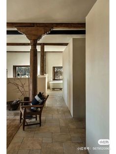 a person sitting on a chair in a room with stone flooring and exposed beams