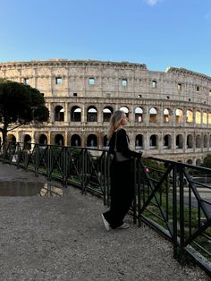 a woman standing in front of the colossion looking out at the street below