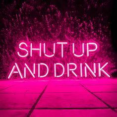 a neon sign that says shut up and drink in front of some trees with purple lights