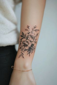 a woman's arm with a flower tattoo on her left wrist, and a gold bracelet