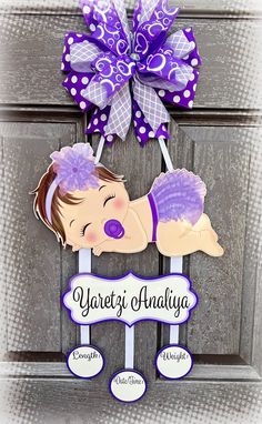 a purple and white door hanger with a baby's name on it