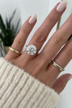 a woman's hand with three different rings on her fingers and one is wearing a sweater