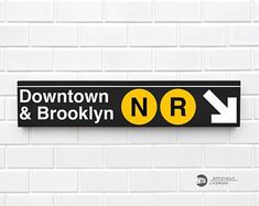 a black and yellow street sign on a white brick wall with an arrow pointing to the right