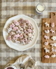 a table topped with lots of cookies and sprinkles next to a glass of milk