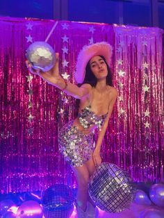 a woman in a sequin dress and hat holding a disco ball