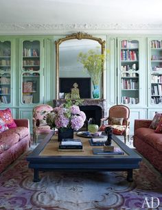 a living room filled with lots of furniture and flowers on top of a coffee table