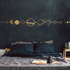 the solar system wall decal is shown above a bed with black sheets and pillows