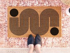 a person standing in front of a door mat with the word moo on it