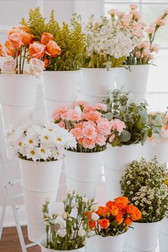 many different types of flowers in white pots