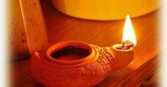 a small clay oil lamp with a lit candle in the middle on a wooden table