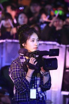 a woman holding a camera in front of a crowd