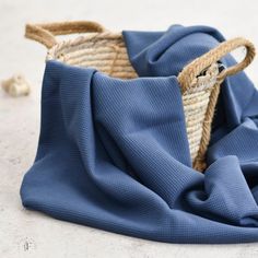 a blue cloth with a woven basket on the floor next to it and some sea shells