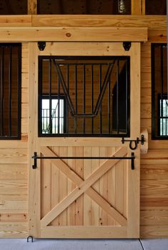 the inside of a horse barn with wooden walls and doors that have bars on them