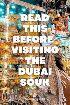 a woman looking at souvenirs in a shop with the words read this before going visiting the dubai souk