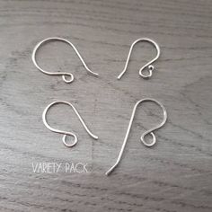 three pairs of silver earwires sitting on top of a wooden table with the words variety pack written below them