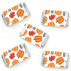 four orange leaves and acorns on a white background with silver foil wrappers