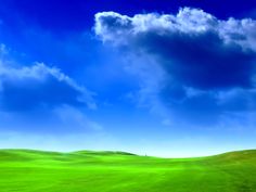 a green field under a blue sky with clouds