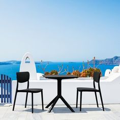 two chairs and a table on a patio overlooking the ocean