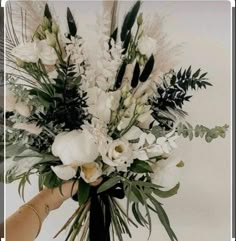 a vase filled with white flowers and greenery