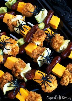 several skewered meats and cheese on sticks with spider web decorations in the middle