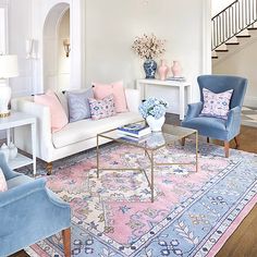 a living room filled with furniture and pink flowers in vases on top of a rug