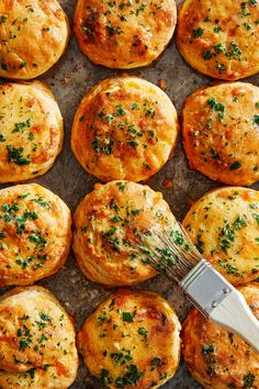 a pan filled with cheesy bread muffins and a whisk