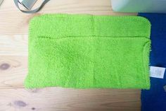 a green towel sitting on top of a wooden floor next to a laptop and mouse