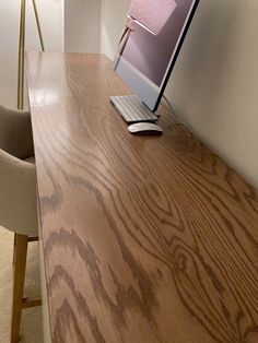 a laptop computer sitting on top of a wooden desk next to a lamp and chair