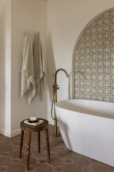 a white bath tub sitting next to a wooden stool