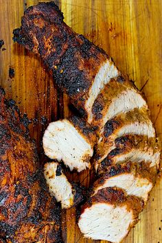 two pieces of meat sitting on top of a wooden cutting board