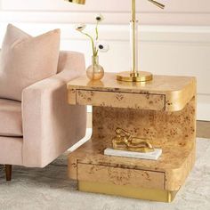 a living room with a pink chair and gold side table