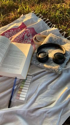 an open book sitting on top of a blanket next to headphones