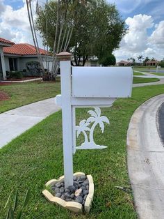 a white mailbox sitting on the side of a road next to a palm tree