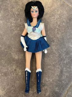 a doll is laying on the floor wearing a blue dress and white top with black boots