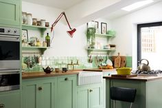 a kitchen with green cabinets and wooden counter tops is pictured in this image, there are pots on the stove