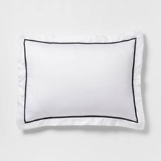 a white pillow with black piping on the front and back side, against a white background